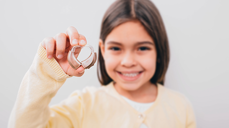 Niña con audífonos en la mano